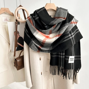 Macro detail of plaid scarf fabric with tassels and a Good Luck woven label tag