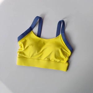 Flat lay of bright yellow yoga sports bra with blue contrast straps and wide underband
