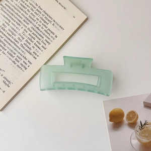 Detail of a large pale green matte shark hair clip on a minimalist desk setup