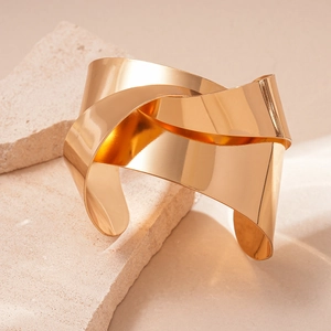 Close-up of polished gold knot bangle showing smooth metallic finish on stone surface