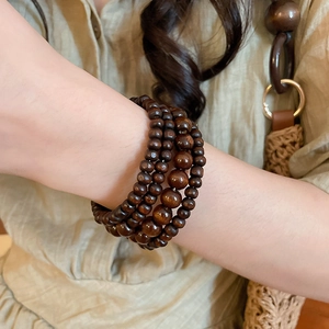 Macro detail of multi-layer deep brown coconut shell wood bead wrap bracelet on wrist