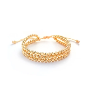 Detail of three-layer gold beaded bracelet with adjustable drawstring closure and polished finish