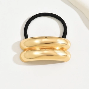 Detail view of a gold metallic curved hair tie with a black elastic band on white background