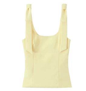 Detail of a cream yellow slim fit top featuring wide shoulder straps with elegant bows