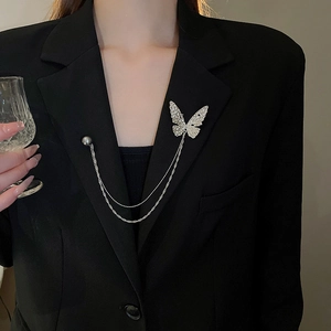 Detail of silver butterfly brooch with tassel chains on a black suit jacket