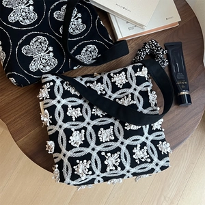 Detailed close-up of butterfly embroidery and 3D flower applique on black canvas bags