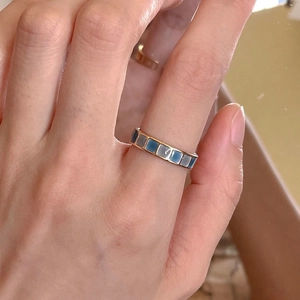 Adjustable golden ring with emerald blue and white enamel inlay on a female hand