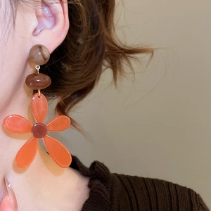 Close-up of vintage resin flower tassel earrings with orange petals on a female model