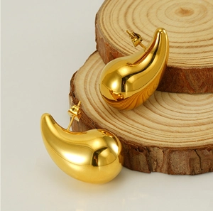 Macro shot of 18K gold teardrop earrings on rustic wooden slices with polished finish