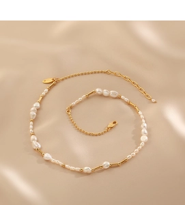 Detail of baroque freshwater pearl necklace with gold beads on champagne silk background