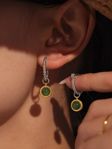 Close-up of green agate drop earrings with silver twisted hoop and gold-plated bezel detail