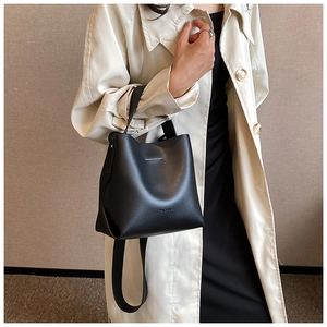 Urban lifestyle shot of black leather bucket bag with top handle and shoulder strap