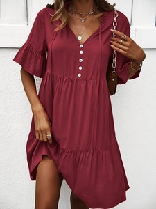 Détail de la robe rouge à col en V avec manches volantées et boutons décoratifs
