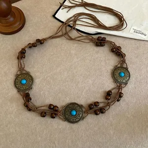 Detail of bohemian waist chain featuring wood beads and turquoise metal discs