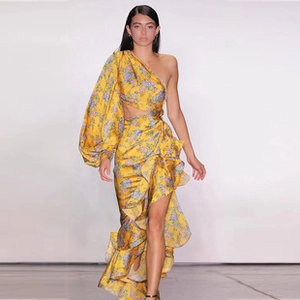 Full view of a floral yellow one-shoulder maxi dress with puff sleeve on the runway