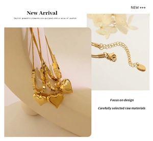 Detail of gold heart pendant necklace featuring snake chain and small square beads