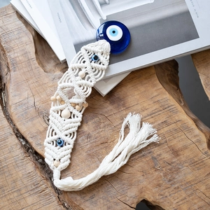 Detail of handmade Macrame Evil Eye wall hanging with blue glass beads and cotton fringe