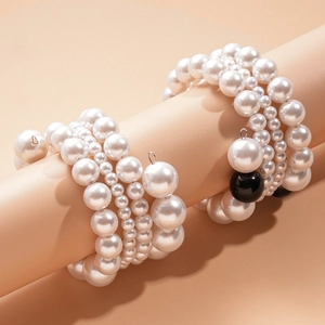Détail d'un ensemble de bracelets multicouches en perles blanches et noires sur présentoir