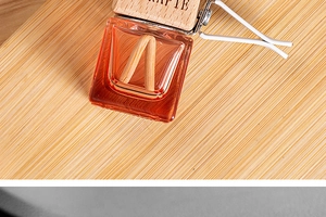 Macro shot of glass car aroma bottle with wood lid and vent clip on bamboo surface