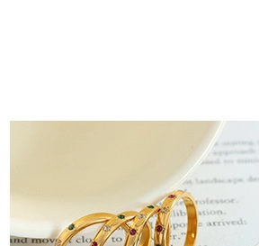 Macro detail of four gold-plated minimalist rings with colorful inset gemstones