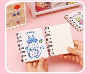 Detail of A7 mini coil notebook showing cute astronaut cat cover and blank pages