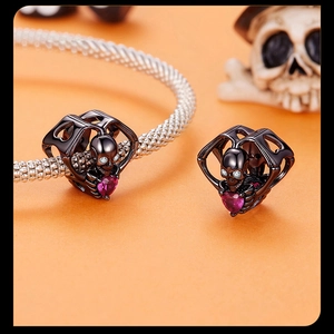 Detail shot of black skeleton charm holding a pink heart gem with crystal eyes