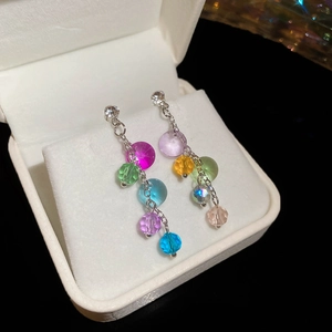 Macro shot of colorful crystal bead earrings with silver chains in a white jewelry box