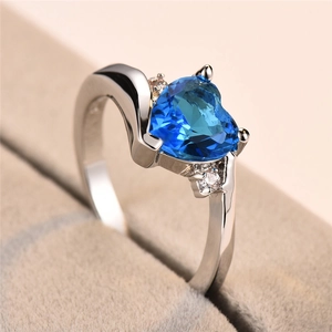 Macro view of heart-cut blue sapphire ring with sparkling side stones in silver band