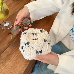 Close-up of beige fuzzy lamb wool cosmetic pouch featuring a black bow pattern