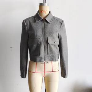 Détail d'une veste en tweed gris avec col à revers, zip métallique et grandes poches