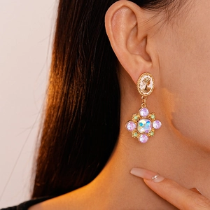 Close-up of vintage portrait earrings with purple rhinestones on a female model