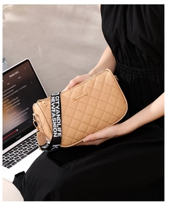 Detail of khaki quilted PU leather bag with black wide lettered shoulder strap on a model