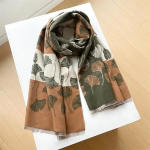 Close-up of thick cashmere-like scarf with ginkgo leaf pattern and tassel details