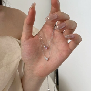 Detail of silver S925 necklaces with pink and white heart-shaped zircon pendants on model