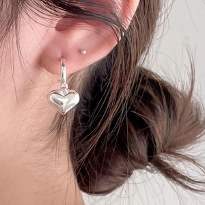 Minimalist 925 sterling silver heart dangle hoop earrings worn by a female model