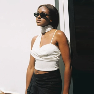 Detail of white one-shoulder tie-up crop top showing slim fit texture and fabric draping