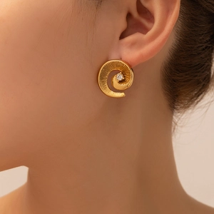 Detail of twisted gold flower earring with a central zircon stone worn by a model