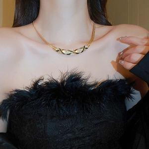 Close-up of vintage curved gold necklace with pavé rhinestones on a fashion model