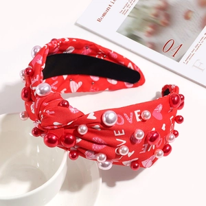 Detail of red fabric knotted headband with LOVE print, hearts, and colorful faux pearls