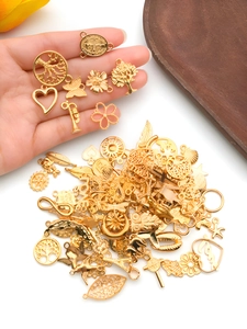 Detail of assorted gold alloy charms for DIY jewelry making held in hand for scale