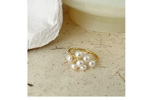 Macro shot of gold ring featuring a clustered white pearl floral design on stone background