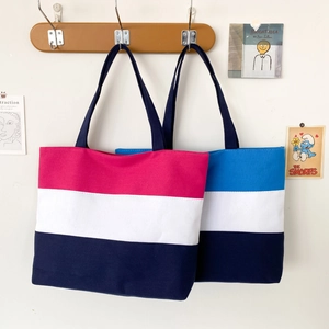 Detail view of large canvas tote bags in red, blue, and white tricolor patchwork on hooks
