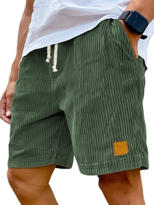 Close-up of dark green corduroy shorts with drawstring waist and square leather patch