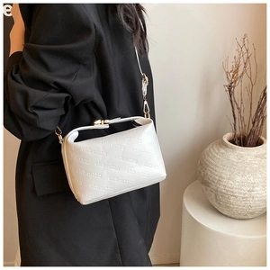 Detail of white cross-body bag featuring embossed rich rabbit lettering and gold hardware