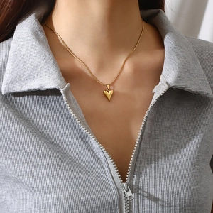 Collier avec pendentif coeur en acier inoxydable plaqué or 18 carats sur un mannequin femme