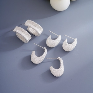 Macro detail of silver frosted geometric C-shape stud earrings with matte texture