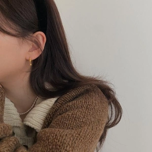 Close-up of a minimalist golden hoop earring with a small bead on female model