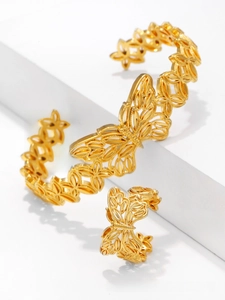 Close-up of gold-plated butterfly bangle and ring set with intricate cutout leaf patterns