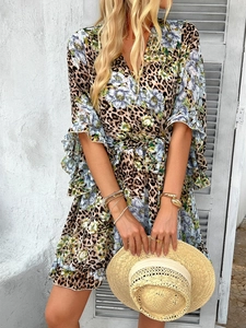 Detail of summer chiffon dress with leopard and floral print held with a straw hat