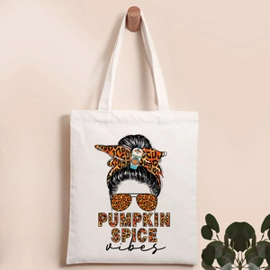 Detail of canvas tote bag featuring Pumpkin Spice vibes illustration on a wooden hook